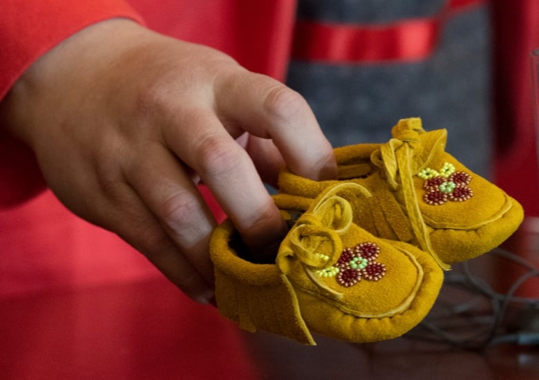 A pair of children’s moccasins represents the tens of thousands of First Nations children who are forcibly removed from their homes, communities and families.