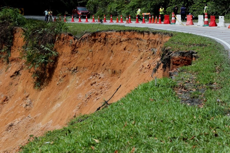 A road is shown adjacent to a hillside that has broken away due to a landslide.