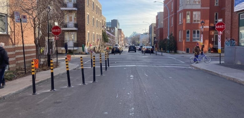 A street with black-and-yellow bollards squeezing in on the left. 