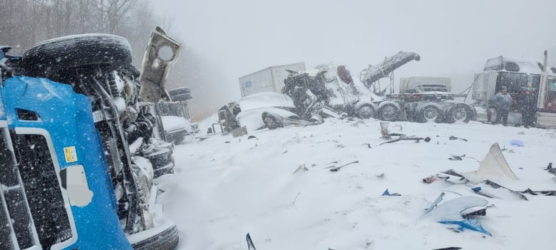 A scene of carnage including debris and destroyed vehicles strewn across the shoulder and side of the highway