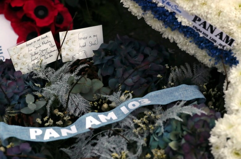 Close-up view of floral wreath with a banner across it that reads Pan Am 103.