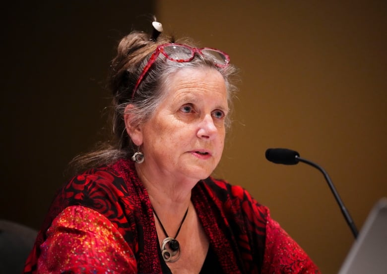 A woman speaks at a microphone.