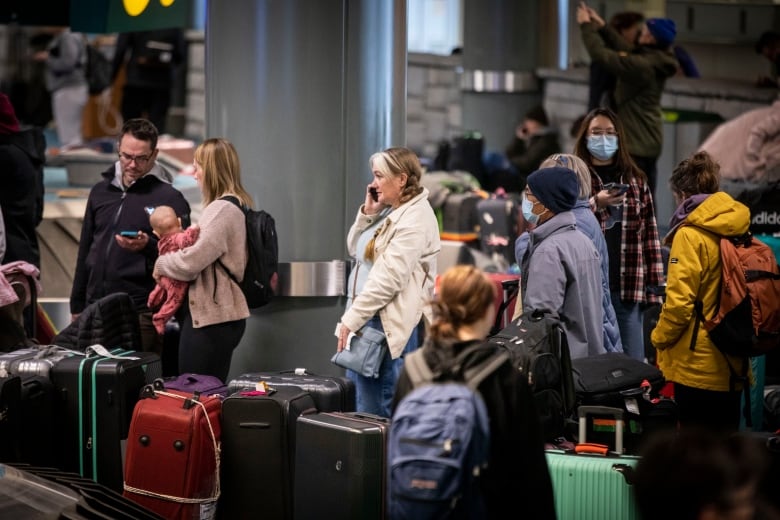 Travellers are pictured in an airport luggage area.