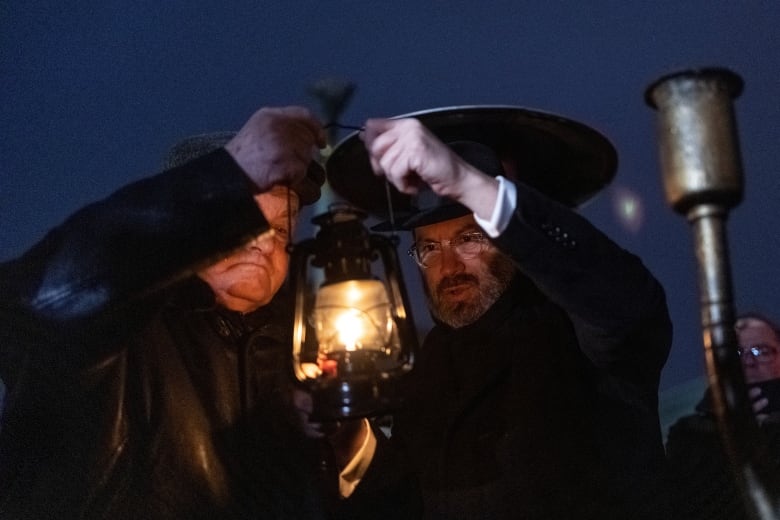 A rabbi lights a candle for a menorah in Kyiv.