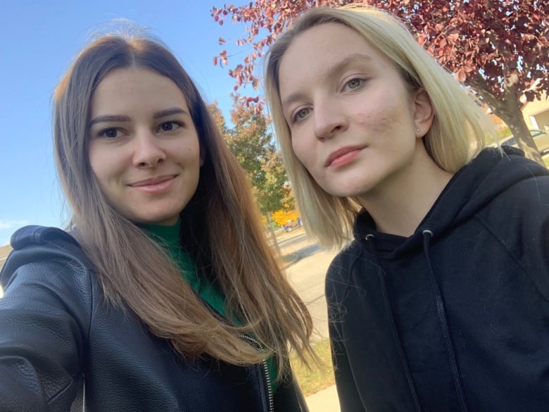 Two women stand outside side by side. 