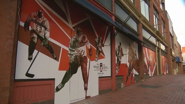 Ads on outdoor wall of building showing hockey players skating.