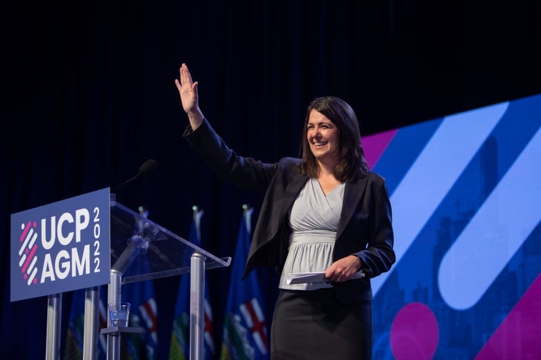 A woman waves to a crowd.