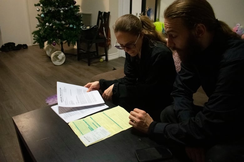 Two people sitting, looking at documents.