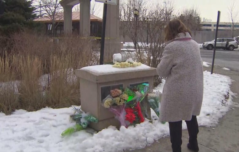 A woman looks at a memorial outside a condo complex.