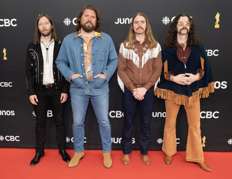 Four men posing on the Junos red carpet wearing retro Western-inspired looks including bolero ties, cowboy boots, western shirts and plenty of fringe and denim.  