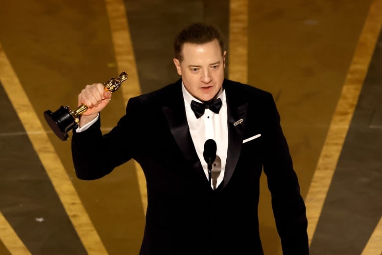 A man holds up an Oscar statue.