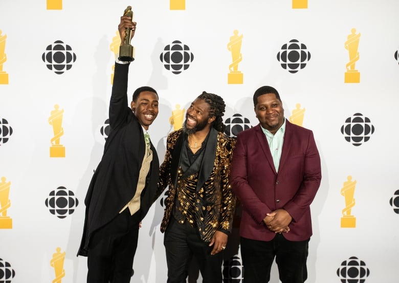 Three men in suit holding an award