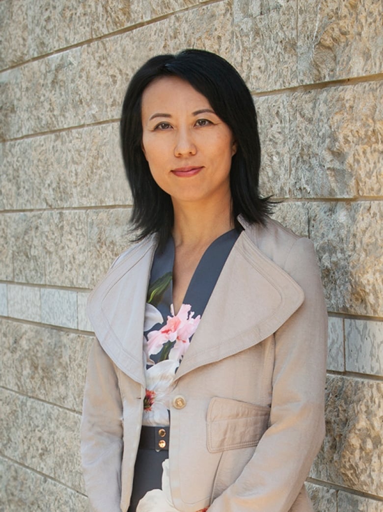 Jia Wang standing in front of a brick wall.