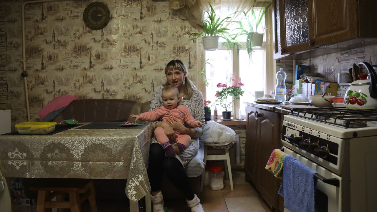 Tetiana Pavelko sits at her kitchen table with Kira on her lap. 