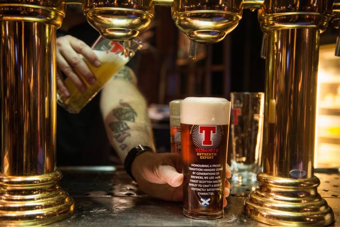 A bartender pours pints of Tennent’s