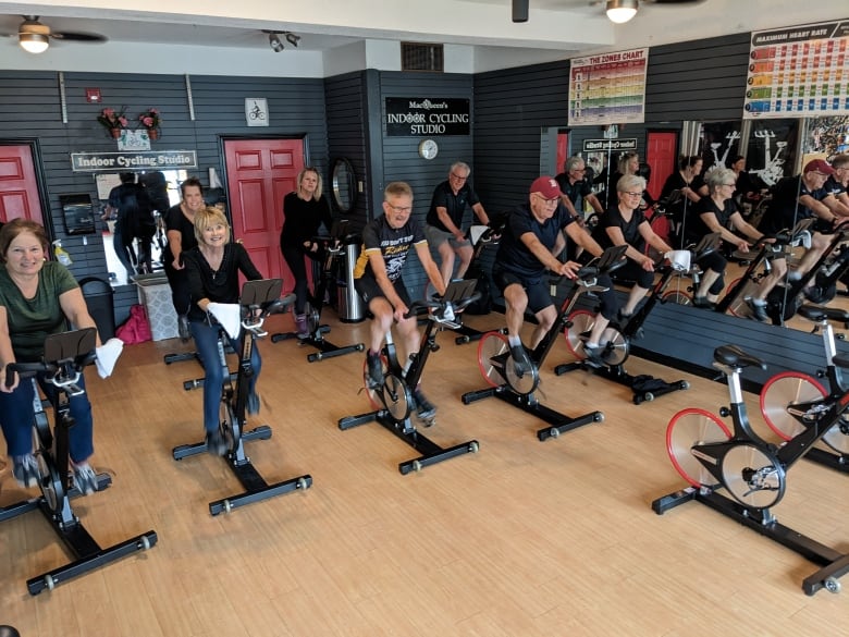 A group of people on stationary bikes in a studio. 