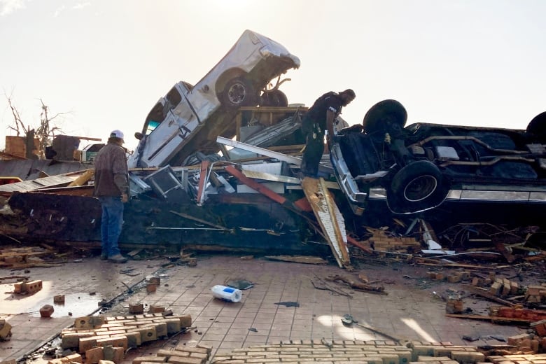 People standing near a pile of tornado-strewn debris