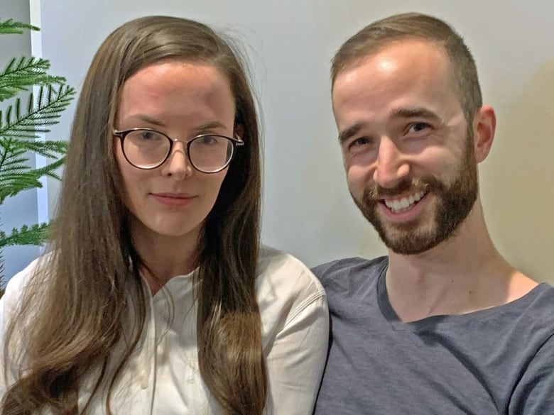 A woman with long dark hair and glasses sit beside a smiling, bearded man.