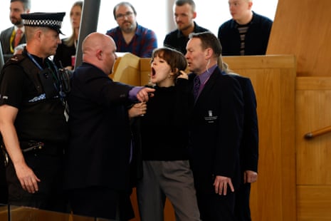 Police and security staff escort a protester from the public gallery during FMQs.