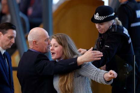 Police and security staff escort a protester from the public gallery at Holyrood.