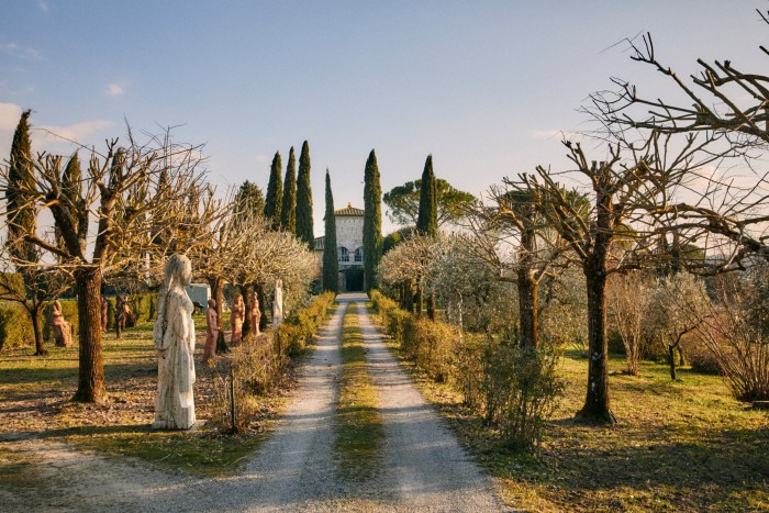 An avenue of pollarded lime trees and statues lead up to the house