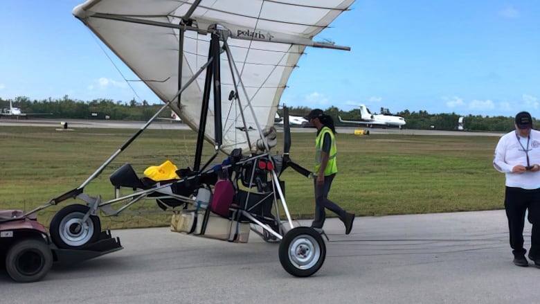 People stand around a hang glider