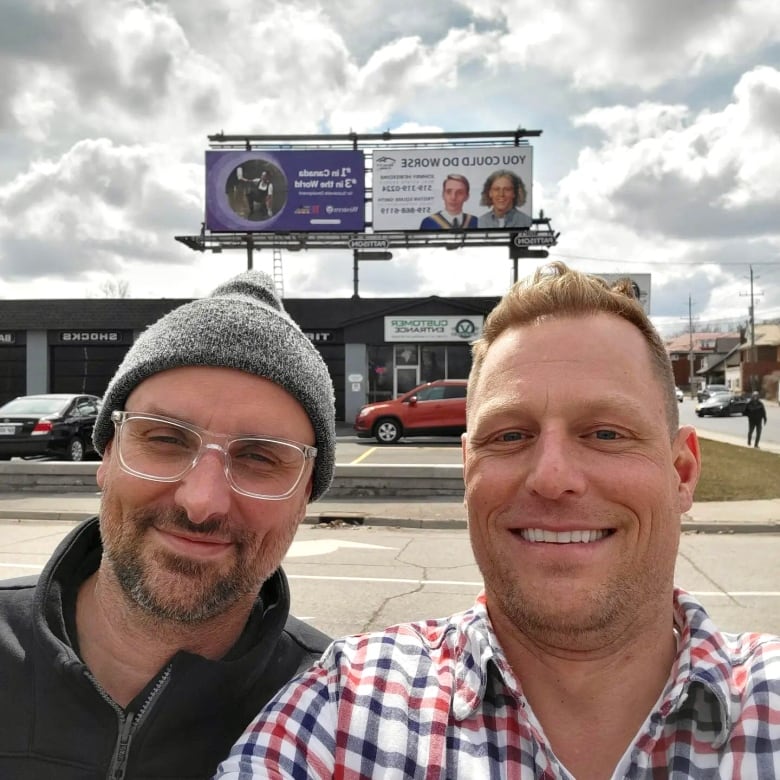 Johnny Hewerdine and Tristan Squire-Smith pose in front of their newly minted billboard on Wharncliffe Road in London, Ont.