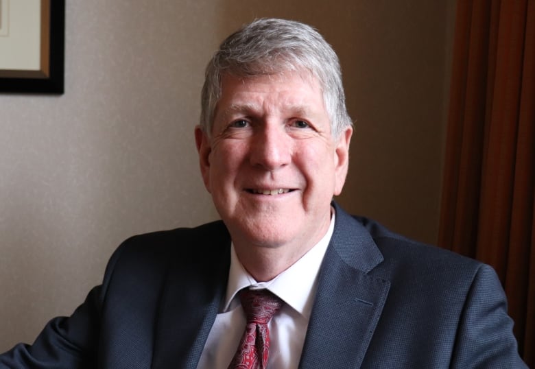 A man sits in a hotel room, smiling to camera