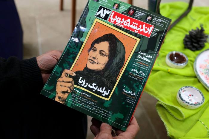 A person holds a copy of a magazine reporting on the case of Mahsa Amini