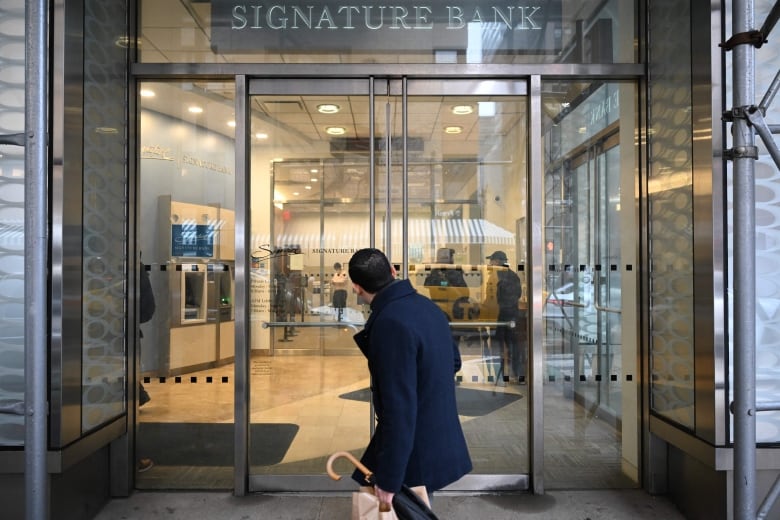 A man walking past a bank.