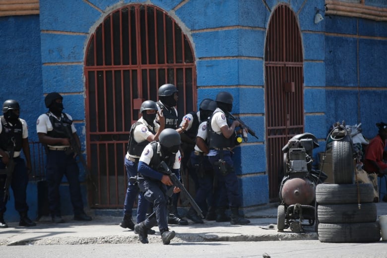 Police officers take cover during an anti-gang operation in the Lalue neighborhood of Port-au-Prince, Haiti, Friday, March 3, 2023.