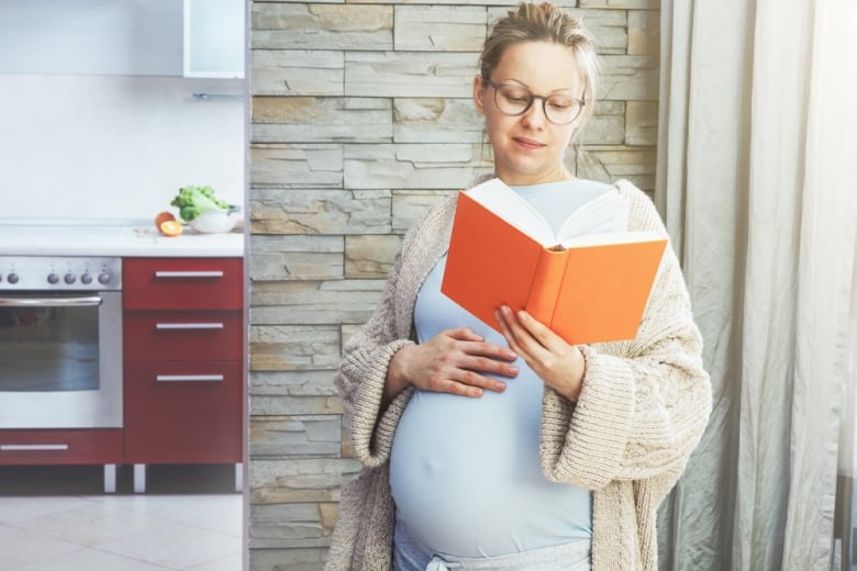 A pregnant woman reads a book.