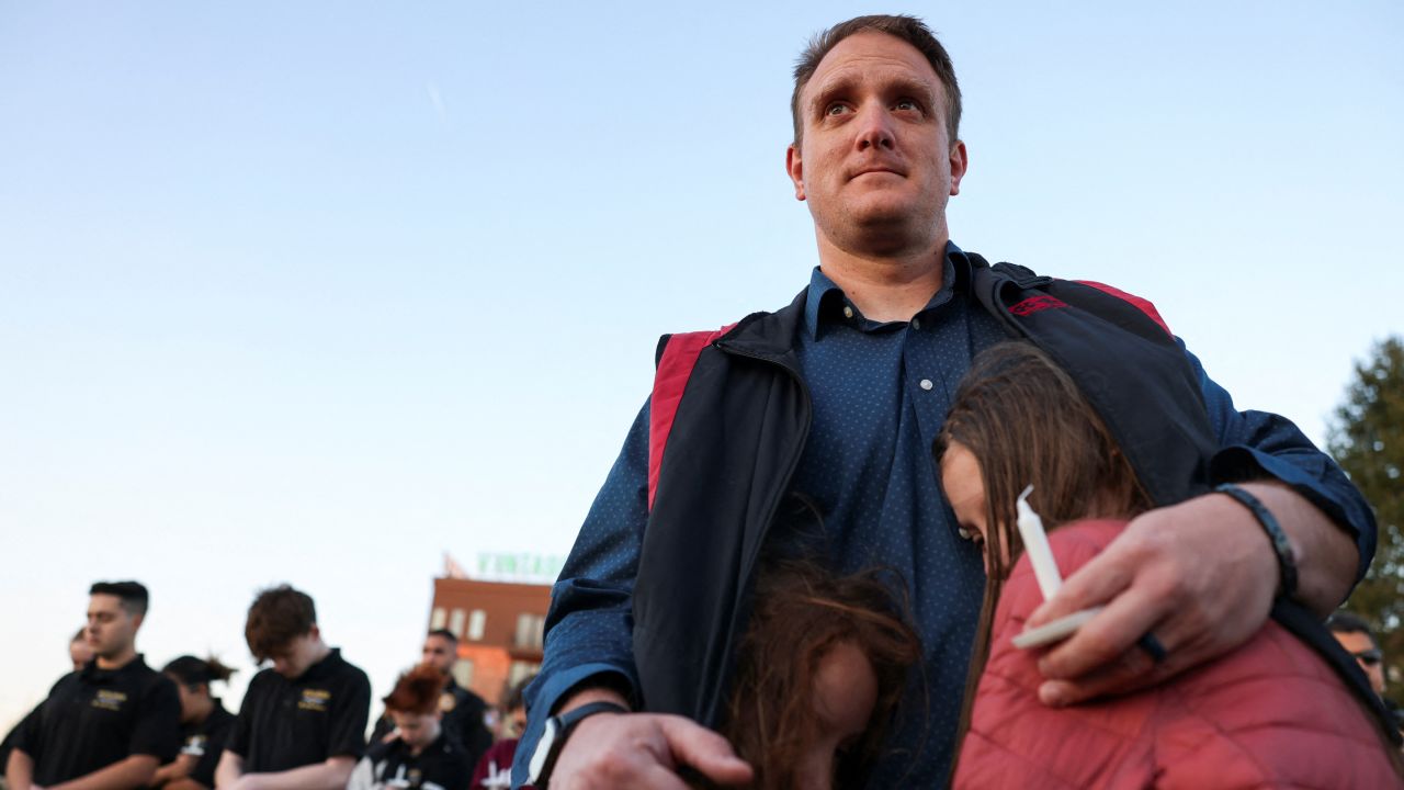 R.T. VanOrden shields his daughters from the wind during a vigil for the victims of a deadly shooting at the Covenant School in Nashville, Tennessee, Tuesday.