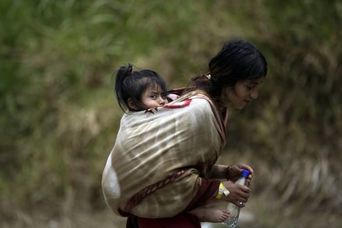 An Ecuadorian migrant carries her daughter while they wait to be transferred by canoe from Quebrada Leon to Bajo Chiquito, in Darién 