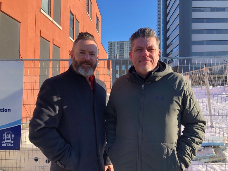 Two men in front of a construction site. 