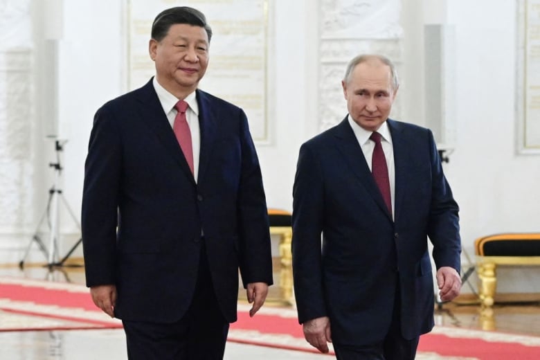 Chinese President Xi Jinping and Russian President Vladimir Putin walk together in the Kremlin in Moscow.