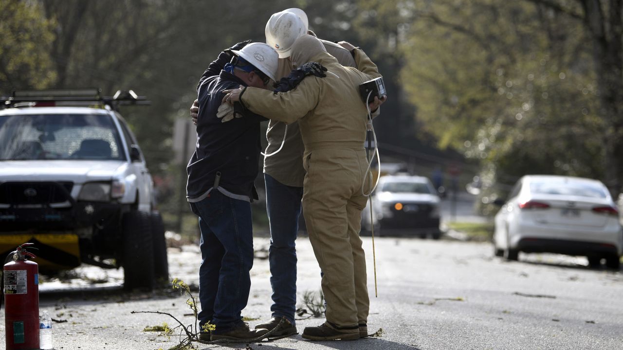 A team from Summit Energy say a prayer together before investigating a burst gas line in Cammack Village, Arkansas, near Little Rock, after a tornado swept through the area Friday.