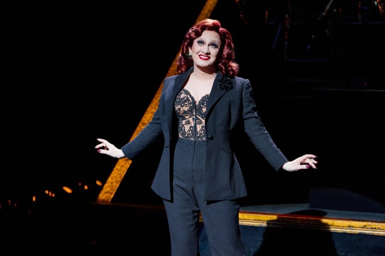 Performer wearing a black pant suit, with a black lace bodice.