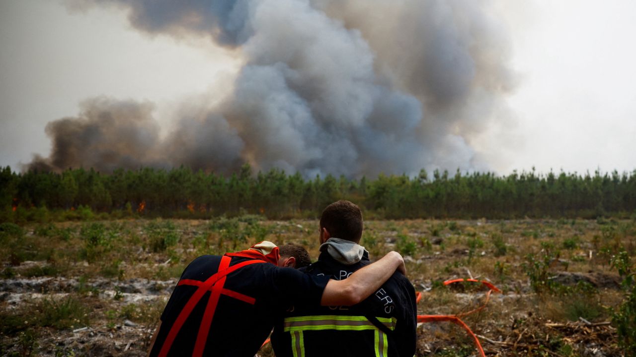 Firefighters embrace as they work to contain a fire in Saint-Magne in southwest France in August 2022.