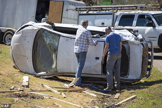 Men inspect a tornado damaged car in Adamsville, Tennessee on Sunday, April 2, 2023