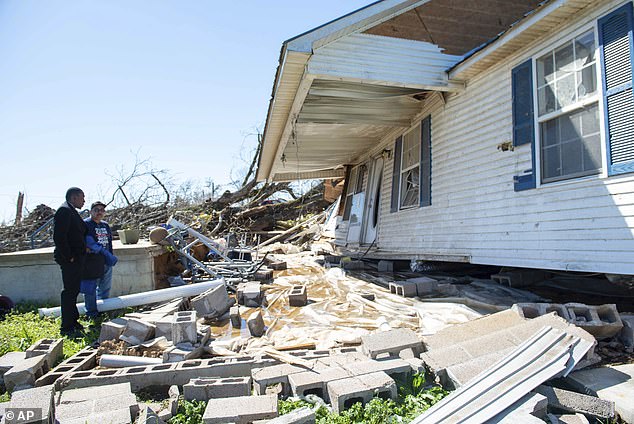 Mike Garcia looks over his tornado damaged house with a friend in Adamsville, Tenn. on Saturday, April 1, 2023