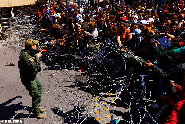 Migrants, mostly from Venezuela, try to cross a barrier, as they take part in a protest at the Paso del Norte international bridge to request asylum in the United States