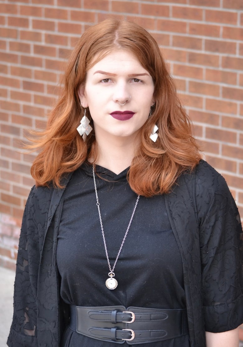 A trans woman with red hair and a black outfit. 