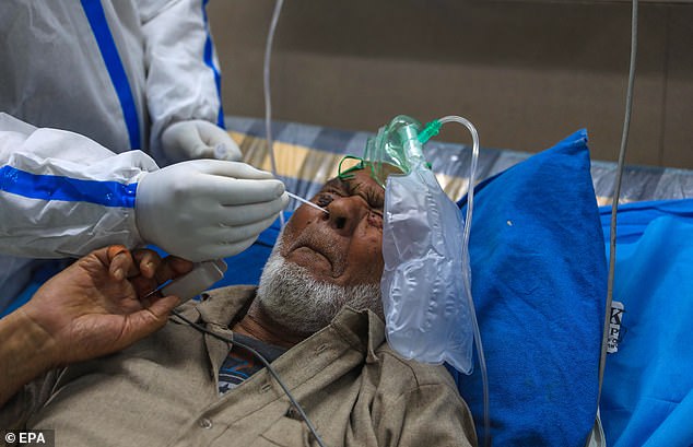 A health worker takes a nasal swab sample from a patient for a Covid test inside a local hospital in Srinagar