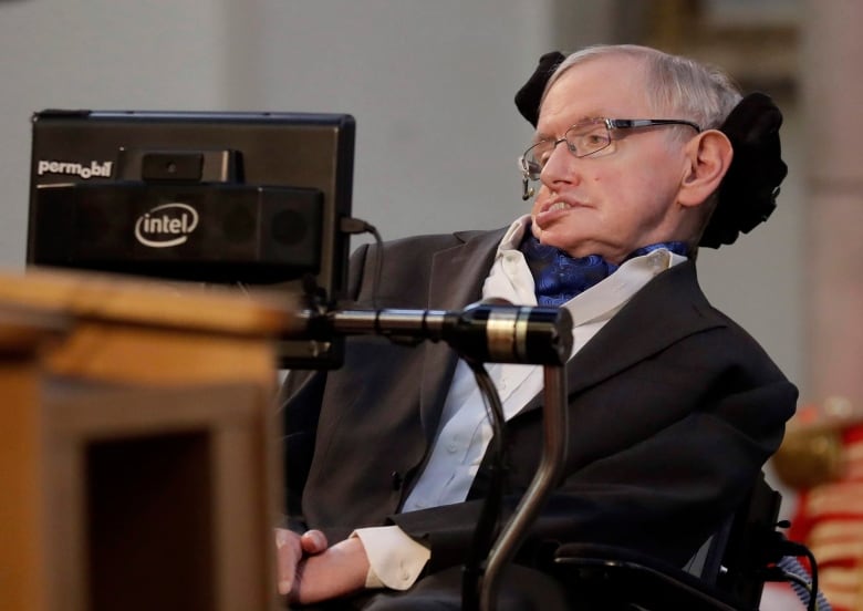 Stephen Hawking is seated in his wheelchair in front of a podium.