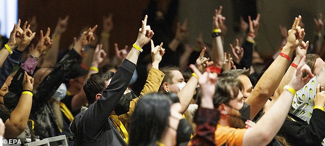 SatanCon attendees flashing the Devil-horns hand symbol as they shout 'Hail Satan' during the opening ceremony