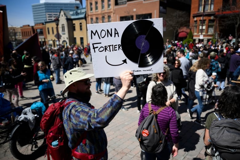 A member of the Public Service Alliance of Canada (PSAC) holds up a sign with a broken record criticizing President of the Treasury Board Mona Fortier, at a picket line outside Place du Portage in Gatineau, Que., on Friday, April 28, 2023. Workers from Canada's largest federal public-service union remain on strike across the country. 