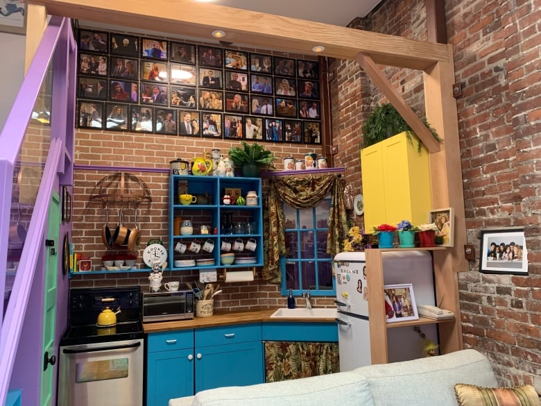 A kitchen with brick walls and teal cabinets, resembling the one in the hit series Friends. 