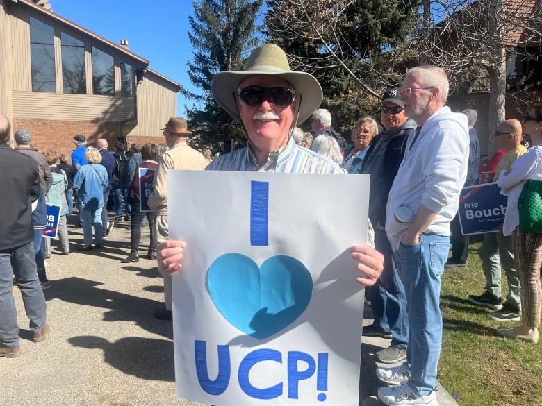 A man stands with a sign that says I love the UCP.