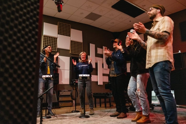 People stand around a microphone and sing.